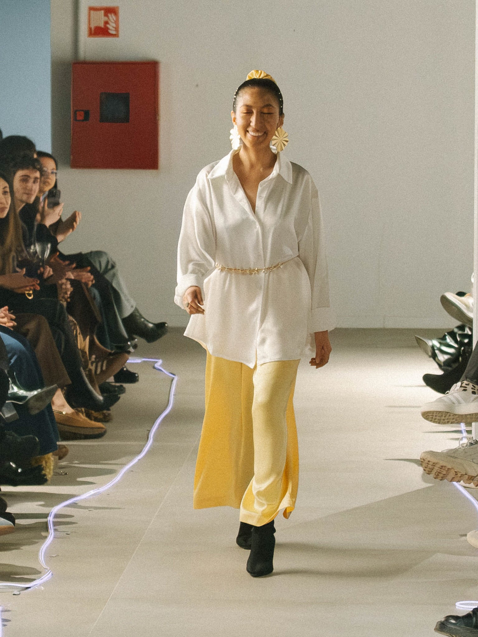Model walking on a fashion show runway wearing a white Moonlight shirt and yellow candlelight pants.C andlelight Pants Yellow — sustainable wide-leg trousers by Halfen House.