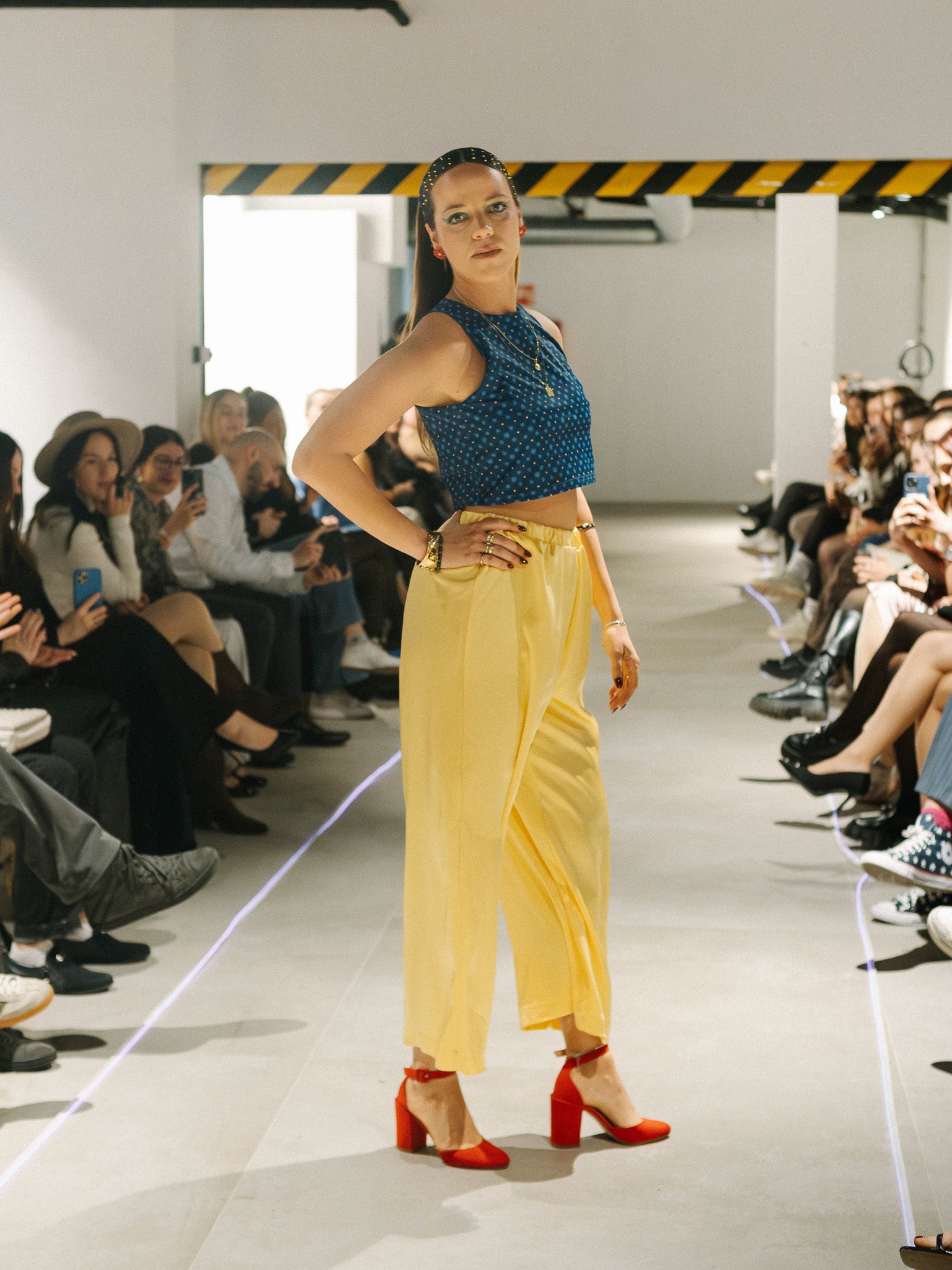 Model walking on a fashion show runway wearing a blue top and yellow pants. Candlelight Pants Yellow — sustainable wide-leg trousers by Halfen House